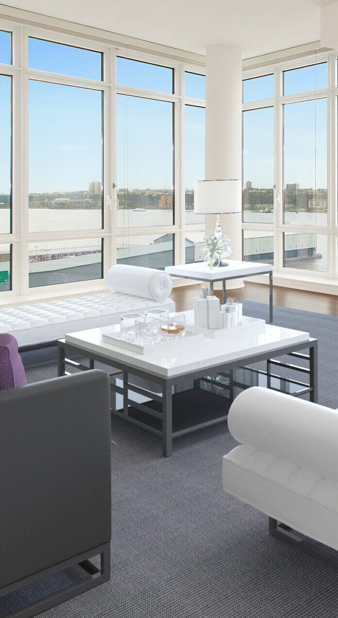 Modern living room at The Aldyn with large floor-to-ceiling windows, white furniture, a black and white coffee table topped with glassware and flowers, plus stunning city and river views in the background.